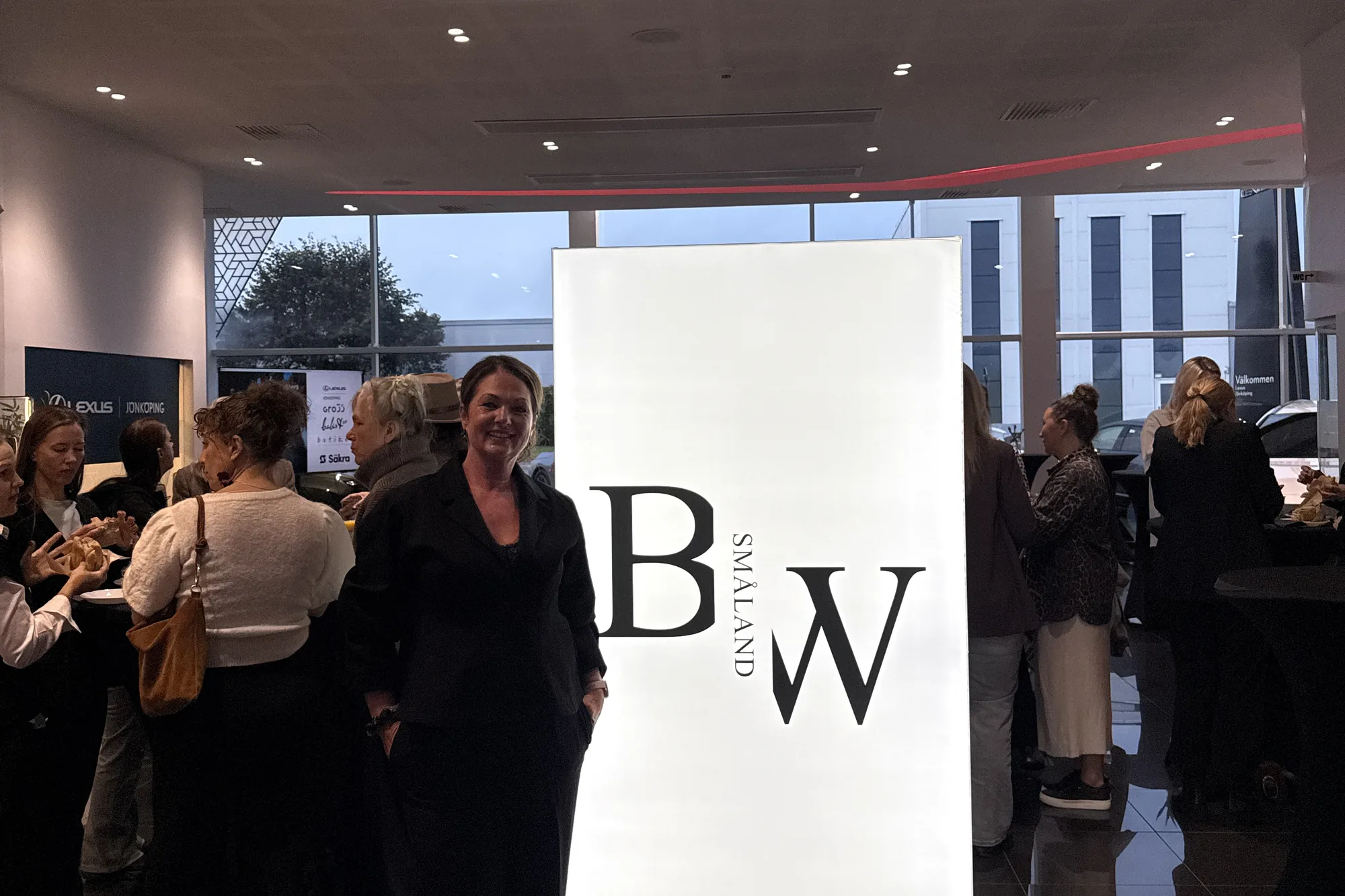 Malin framför Business Women Smålands ljusskylt under minglet på frukostträffen hos Lexus Jönköping